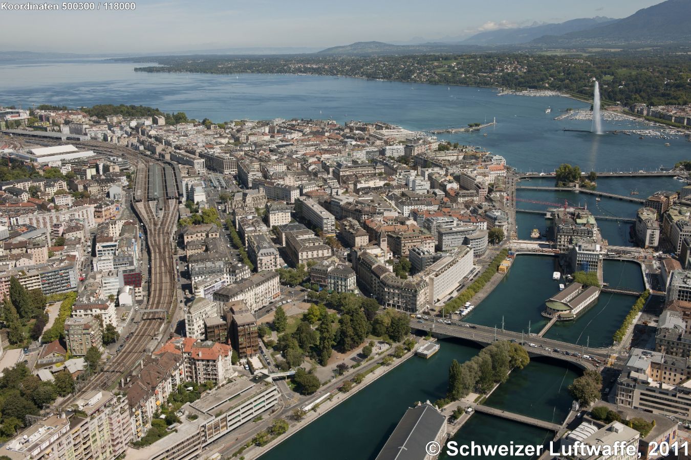 Genf Seebecken mit Jet d'eau und Ausfluss der Rhone, 'Ile Rousseau' (Position 2'500'302.29, 1'118'091.96). Rechts im Bild knapp sichtbar: Stadtteil Eaux-Vives, links (gegen W) Stadtteil St-Gervais und Bahnhof SBB / SNCF.